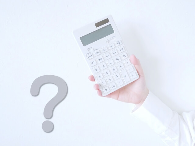 手に持った電卓とクエスチョンマーク