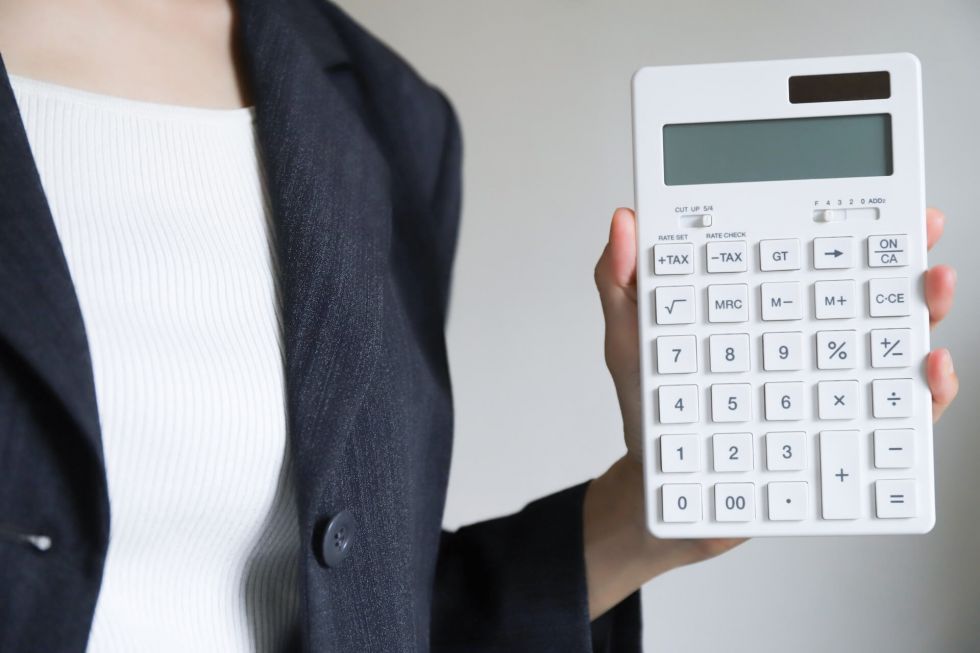 スーツ姿の人が持つ大きな電卓